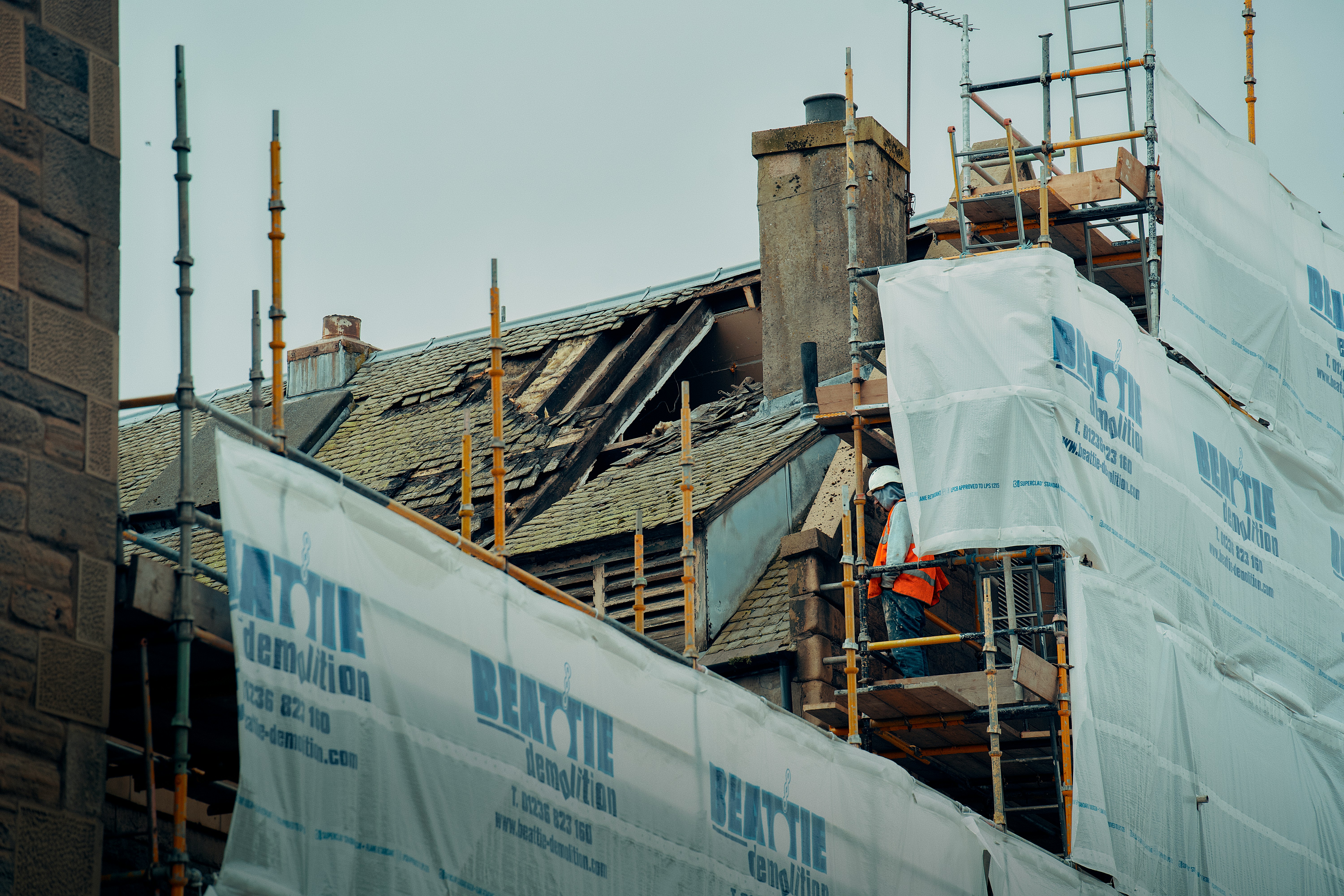 Fire damaged property with scaffolding and roof damage under repair